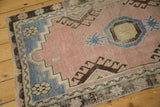 Vintage distressed Oushak rug with muted blush field, pale blue geometric accents, and visible wear.