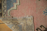Distressed blush pile of vintage Oushak rug, showing localized foundation, fringe, and woven back.