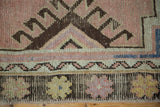 Distressed vintage Oushak rug border with blush, saffron, and charcoal brown geometric motifs.
