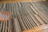 Hand woven Moroccan Kilim patchwork carpet with horizontal seams and varied stripes.