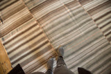 Patchwork kilim rug featuring horizontal brown, ivory, and silver striped panels.