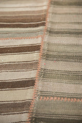 Close-up of vintage Moroccan Kilim patchwork with peach seam, uniting striped brown and muted wooded tones.