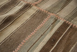 Detailed view of hand woven Moroccan Kilim patchwork with varied brown stripes and pink seams.