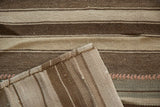 Stitched edge and horizontal bands of brown and ivory on a vintage Kilim patchwork rug.