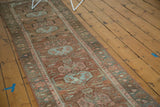 Distressed Malayer runner's central powder blue medallions, elongated leaves, and a patterned outer border.
