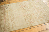 Vintage distressed Oushak rug showing faded blush guls and geometric patterns, with even pile wear.