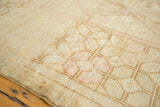 Distressed Oushak rug texture with faded blush geometric motifs and even pile wear.