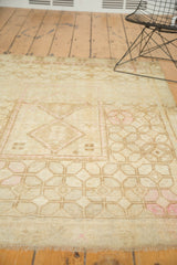 Distressed vintage Oushak rug detail with large repeating geometric guls in ivory and blush.