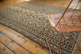 Repeating dark chocolate and dusty mint geometric gul motifs on a vintage Kilim.