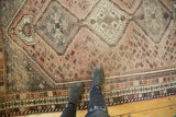 Distressed vintage Shiraz carpet with muted blush, charcoal brown geometric motifs and barber pole border.