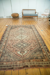 Distressed vintage Shiraz carpet with faded blush, charcoal, and beige triple medallion and playful botehs.