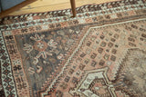 Distressed vintage Shiraz carpet's faded blush, charcoal, and sand field with scattered boteh motifs.