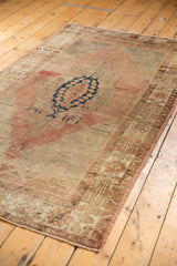 Distressed vintage Oushak rug corner with low pile and faded dusty rose border.