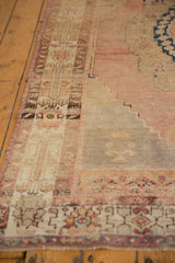 Distressed Oushak runner with faded rose, beige geometric border, low pile, and secured selvage.