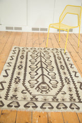 Distressed vintage Kilim corner: geometric ivory, charcoal tree of life pattern, visible fringe.