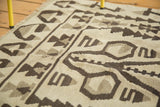 Distressed vintage kilim weave featuring geometric charcoal and silver motifs on antique ivory.