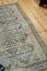 Distressed pile of antique Malayer rug, with beige and brown henna plant motif and wear.