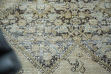 Distressed antique Malayer rug with exposed foundation and lattice henna pattern in muted tones.