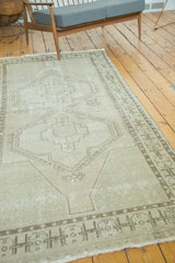 Distressed Oushak rug runner featuring a minimalist medallion and intricate border in neutral tones.