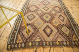 Vintage Turkish village Kilim rug with repeating diamond patterns and fringed end.