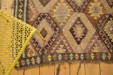 Bottom edge of vintage Kilim rug, geometric diamond pattern in saffron, blush, and chocolate.