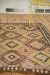 Repeating diamond medallions and geometric border of a vintage Kilim in blush and saffron.