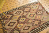 Repeating diamond medallions in saffron, blush, and chocolate on a handwoven vintage Turkish Kilim.