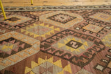 Handwoven vintage Kilim rug with geometric diamond motifs in saffron, mauve, and brown.