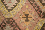 Hand woven kilim detail showing blush, saffron, and chocolate brown diamond lattice motifs.