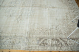 Corner of distressed Oushak rug with visible foundation and soft floral motifs.