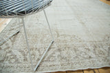 Detail of distressed Oushak carpet with worn pile and faded shadow floral motifs.