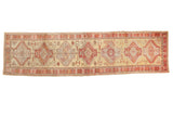 Vintage Turkish Oushak runner with repeating medallions in madder red and beige over a dusty gold field.