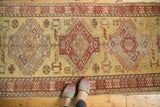 A vintage Oushak runner showing alternating color fills within its geometric red and tangerine medallions.