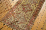 Vintage Oushak runner with repeating medallions and rams horn motifs in dusty gold and red.