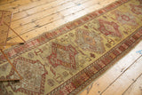 Angled view of a vintage Oushak runner with geometric medallions in madder red on a dusty gold field.
