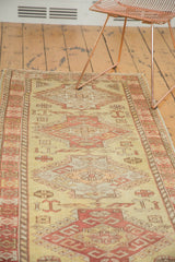 Vintage Oushak runner with warm dusty gold and red geometric motifs shown in a home setting.