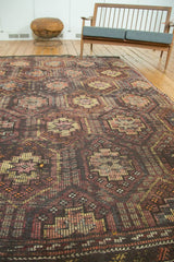 Distressed Jijim carpet showcasing multi-paneled motifs in charcoal, aubergine, and blush.