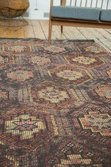Decorative distressed Jijim rug with multi-paneled geometric pattern in charcoal, aubergine, and orange.