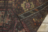 Folded vintage distressed Jijim carpet displaying hand woven texture, geometric charcoal, orange, and blush tones.
