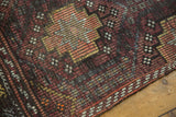 Textured vintage distressed Jijim rug surface, revealing a staggered lattice in charcoal, aubergine, and tangerine.