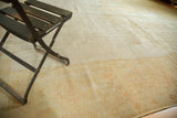 Distressed antique Oushak carpet texture with faded pale sand, gold, and subtle blush tones.