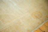 Distressed antique Oushak carpet showing faded pale gold and blush patterns on worn pile.