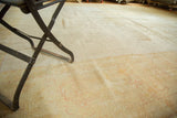Textural detail of the antique distressed Oushak carpet with mostly even wear and pale patterns.
