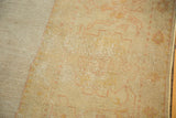 Worn pile and faded geometric motifs in pale sand, ivory, and blush on an antique Oushak rug.