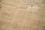 Distressed beige field with scattered cobalt blue pictorial motifs on a Chinese carpet.