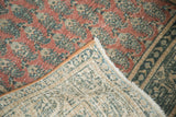 Folded corner of distressed vintage Tabriz rug, showing blush Mir cyprus pattern and beige foundation.