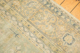 Distressed pile texture with exposed knot heads and pale sage green, apricot floral motifs.