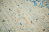 Distressed pile of a vintage Meshed rug, showing sky blue and pale coffee floral patterns.