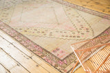 Distressed Khotan runner corner with stepped pink floral motifs, intricate lattice, and visible wear.