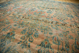 Textured antique Lilihan rug with a distressed blush field, exhibiting rich teal and gold floral motifs.